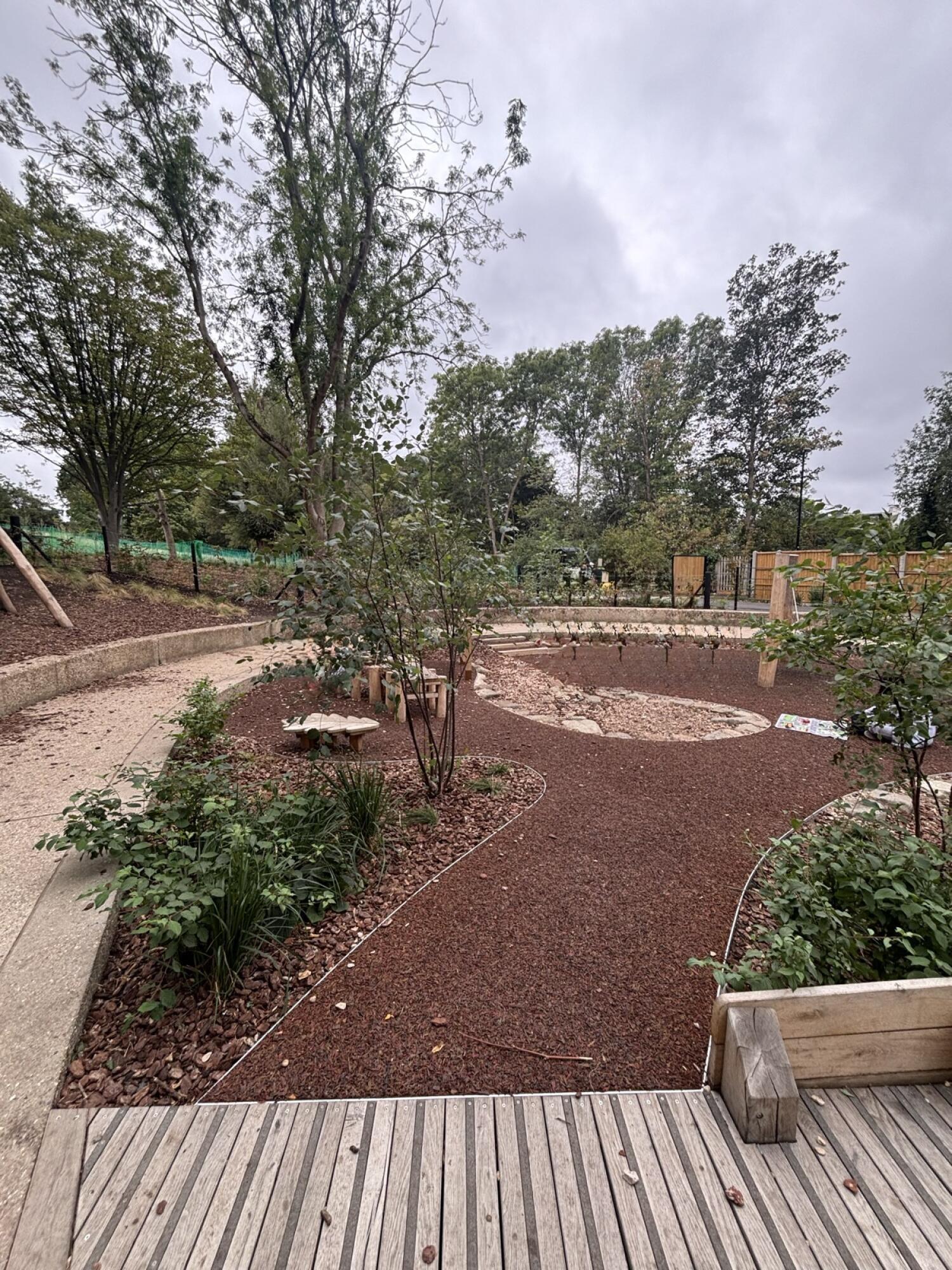 From opening facing left. Path ahead to gravel play area. Plant beds on left and right.
