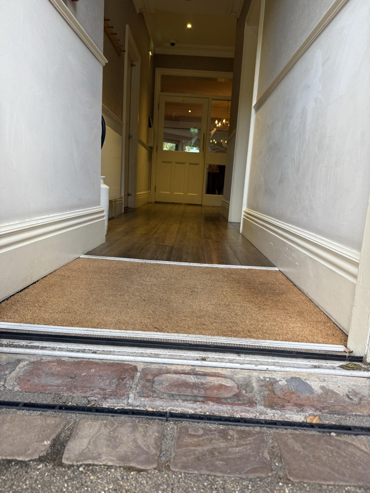 Small bump at foot of door. Doormat after door.