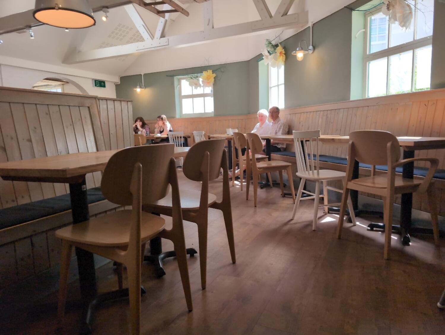 Half booth along left. Tables and chairs in centre. Half booth along right wall.