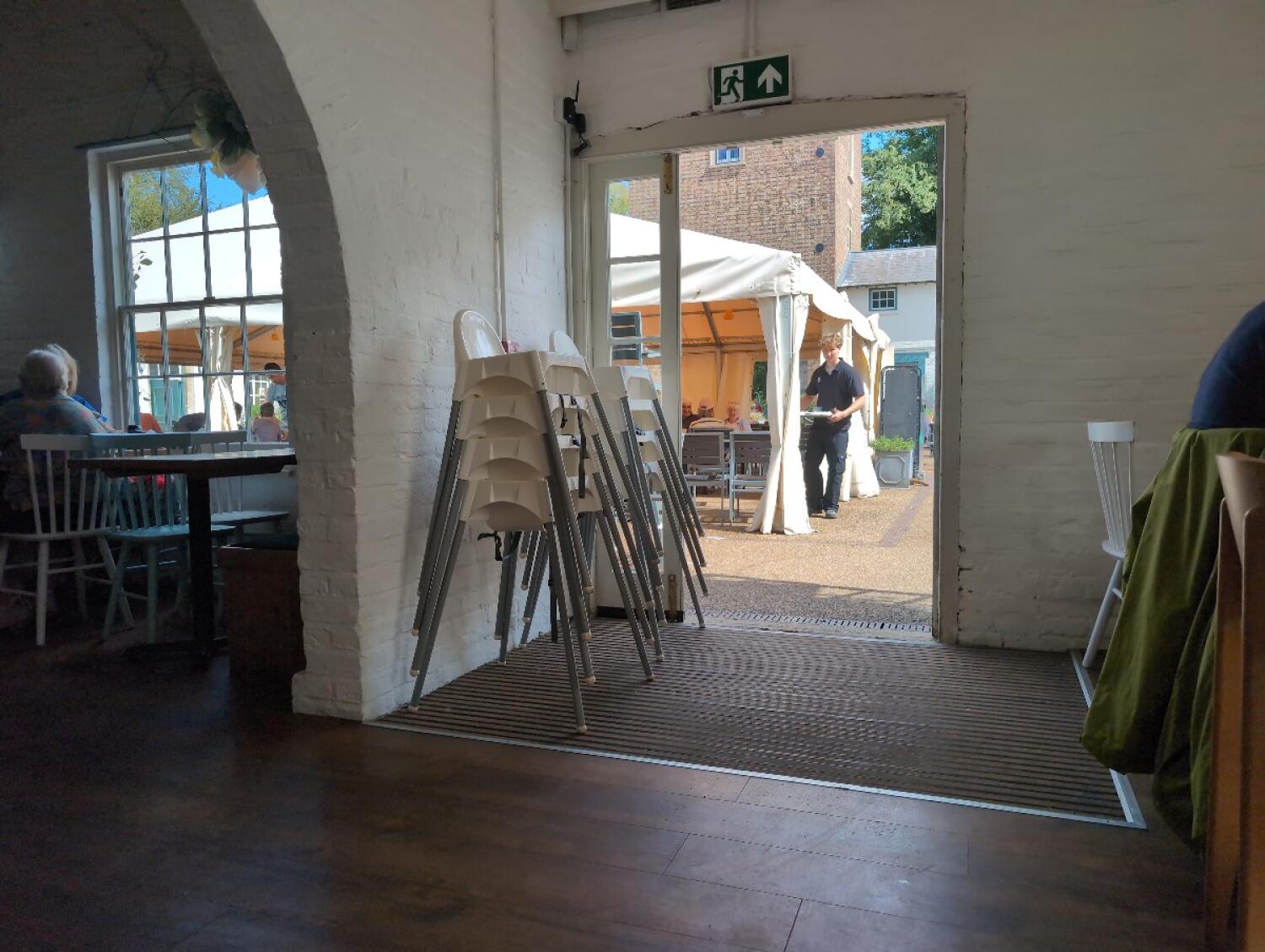 White wood-framed glass doors. Outdoor seating visible beyond.