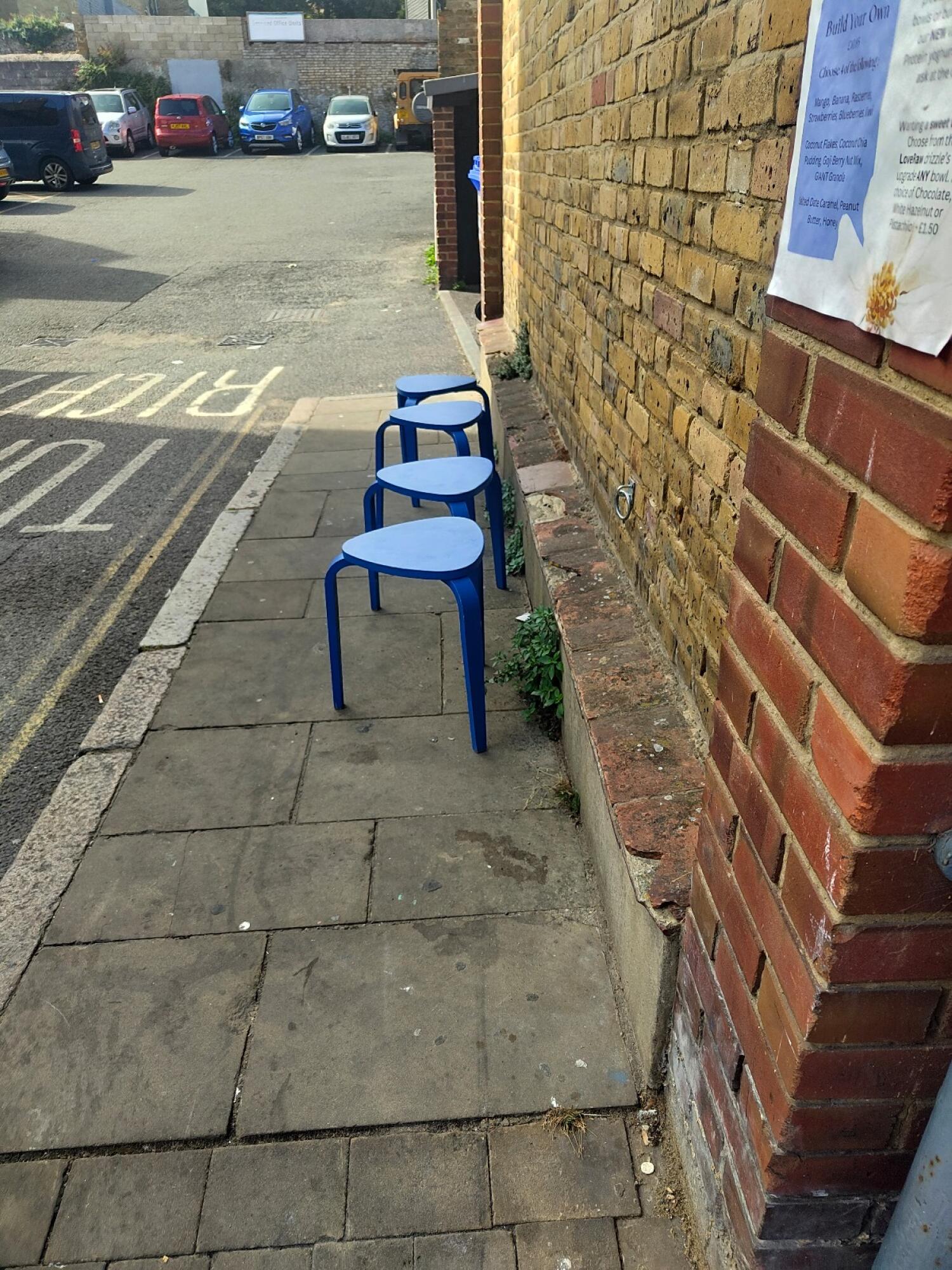 Stools obstruct path along right brick wall.