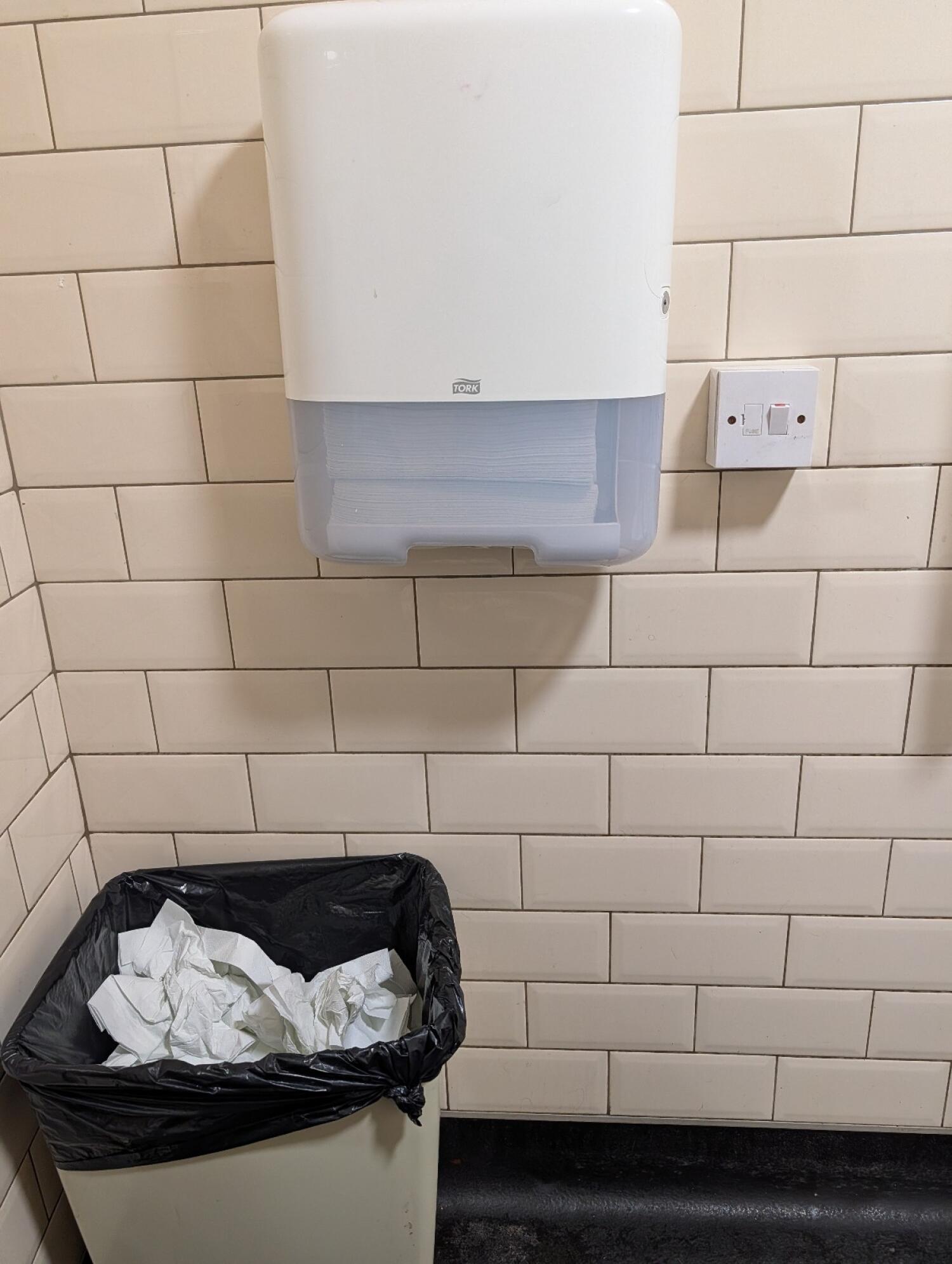 Waste bin below left. Paper towel dispenser centred.