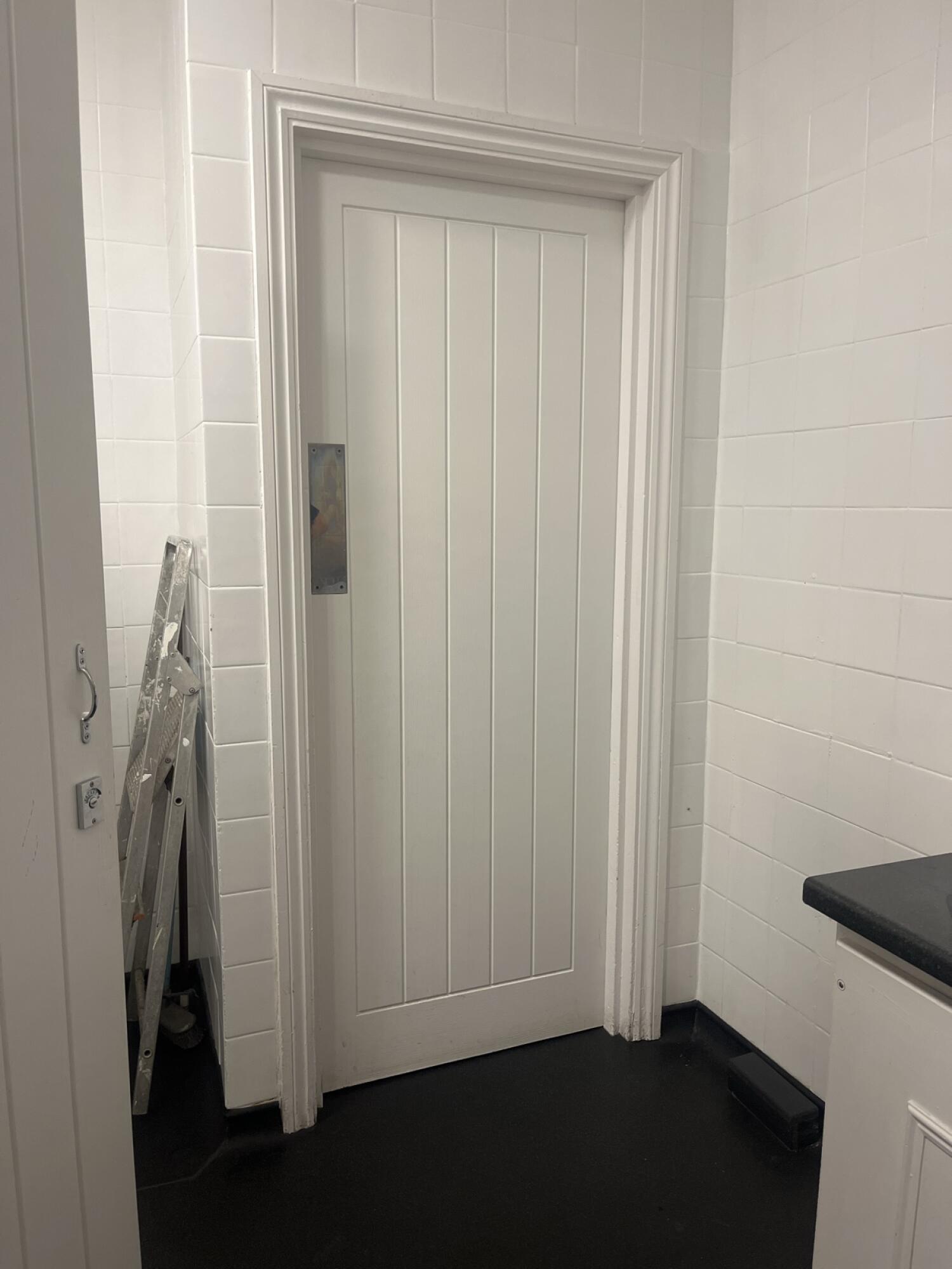 Cream wooden door. Use plate to open.