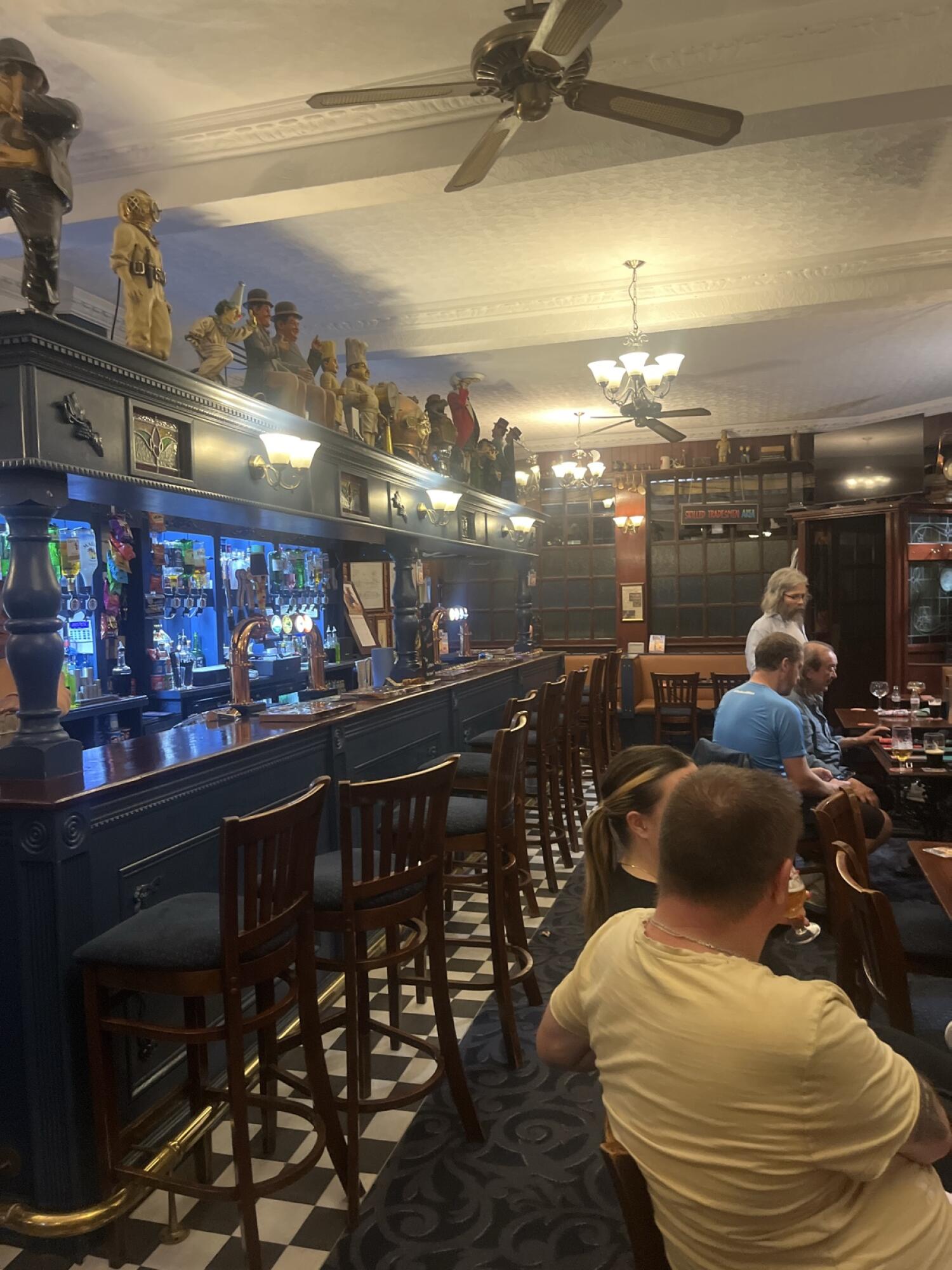Bar counter and stools left. Checkered floor path in centre. Tables and chairs right.