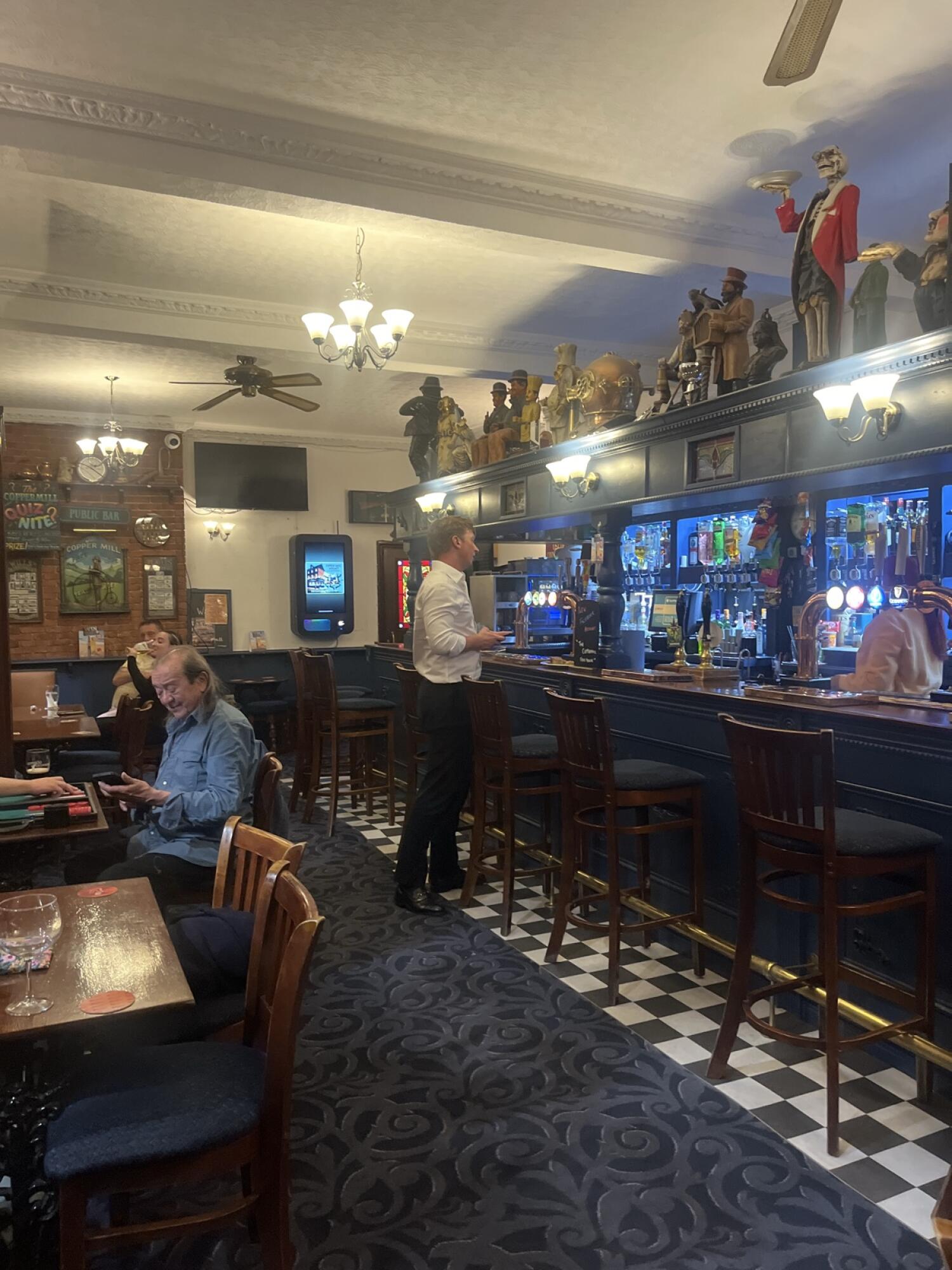 Tables and chairs along left. Carpeted path through centre. Bar counter and stools right.