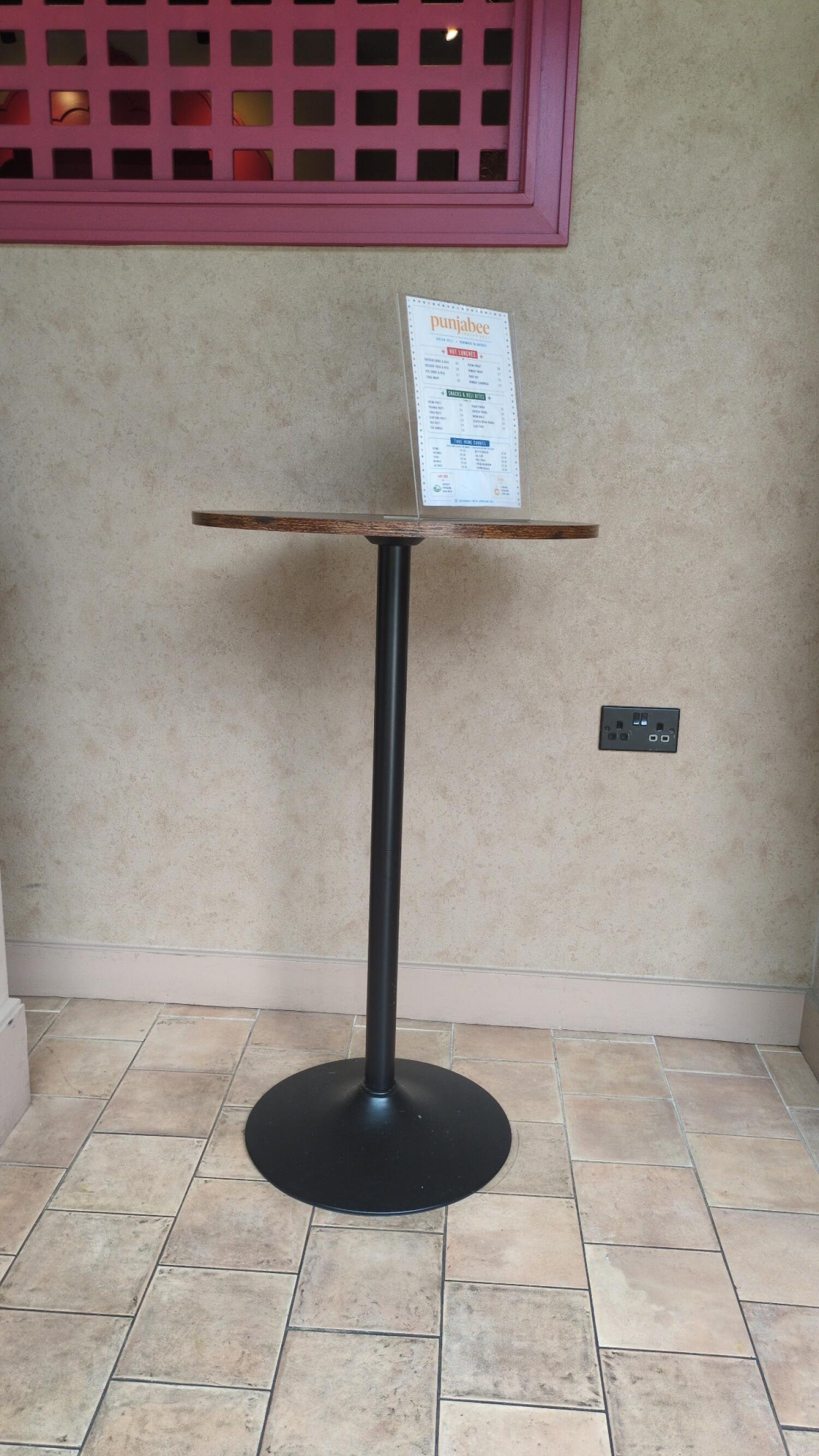 High table in centre. Wall socket on right. Tiled floor throughout.
