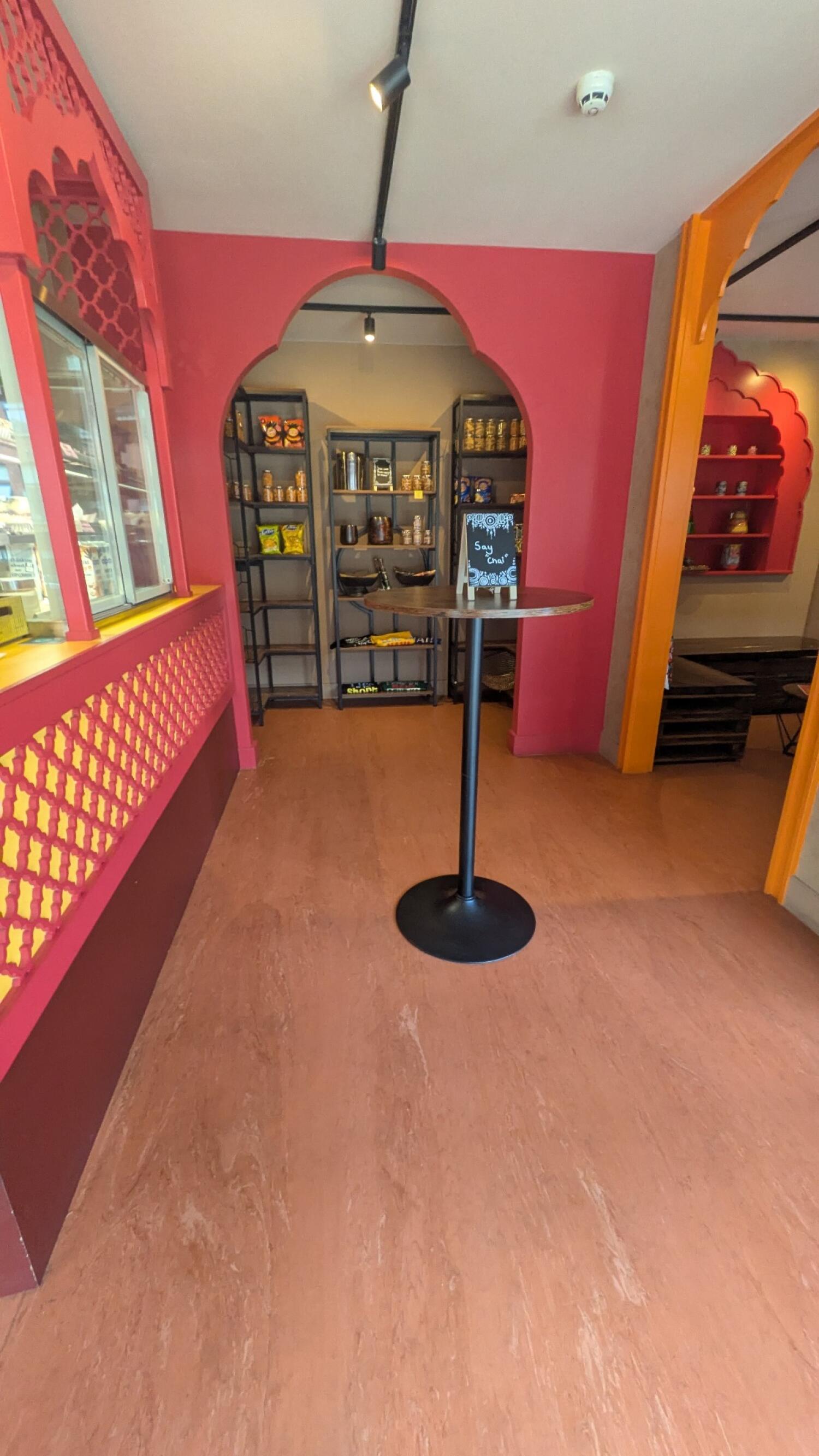 Display fridge along left. High table in centre. Seating area to right.