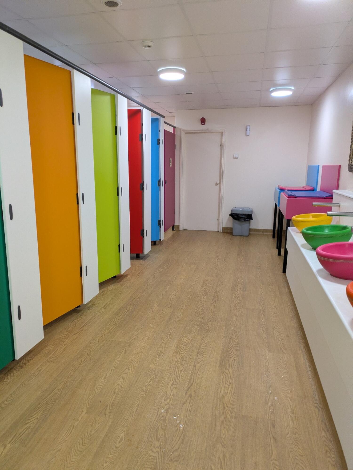 Cubicles along left wall. Sinks and baby changing stations on right.