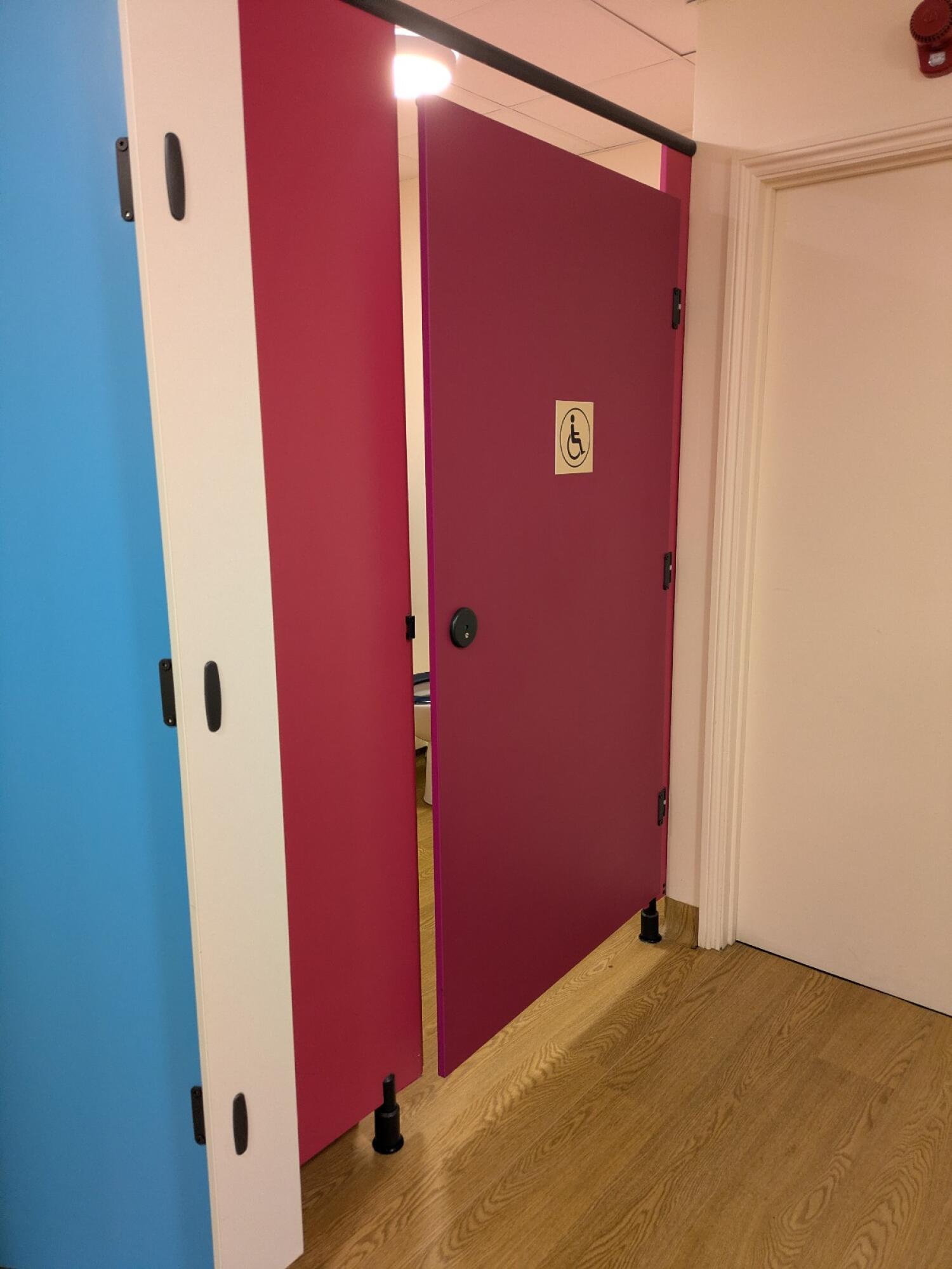 Pink laminate cubicle door. Use handle to open.