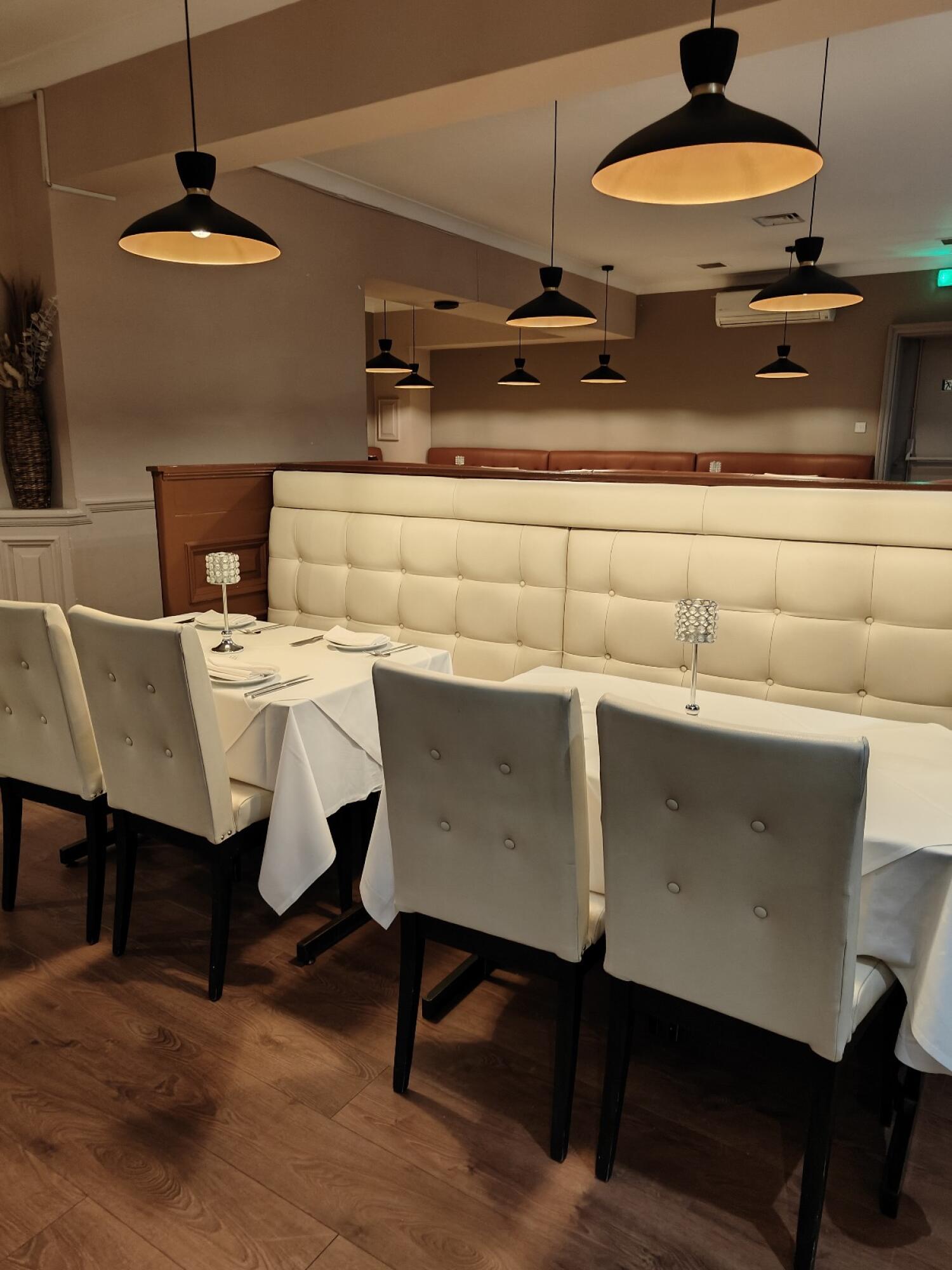 Tables and chairs on left. Half booth in centre. Wooden floor throughout.