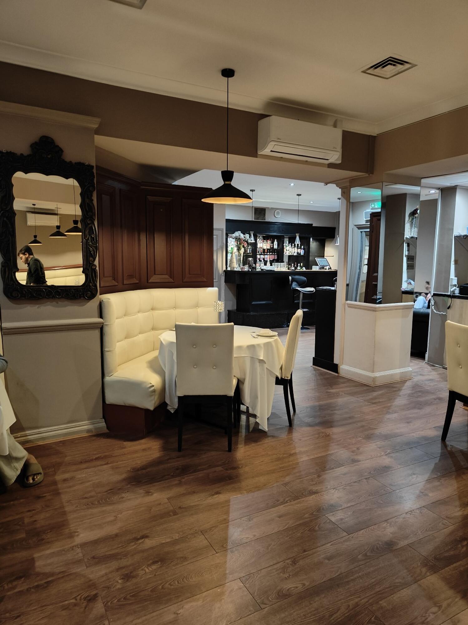 Half booth along left. Open floor to back bar. Pillar and seating on right.