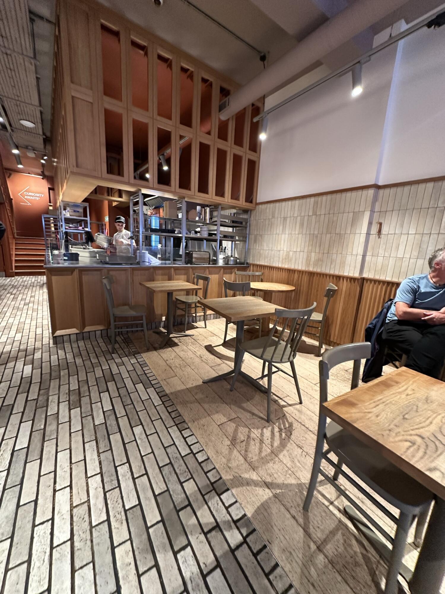 Tiled path and stairs left. Service counter in centre. Tables and chairs along right.