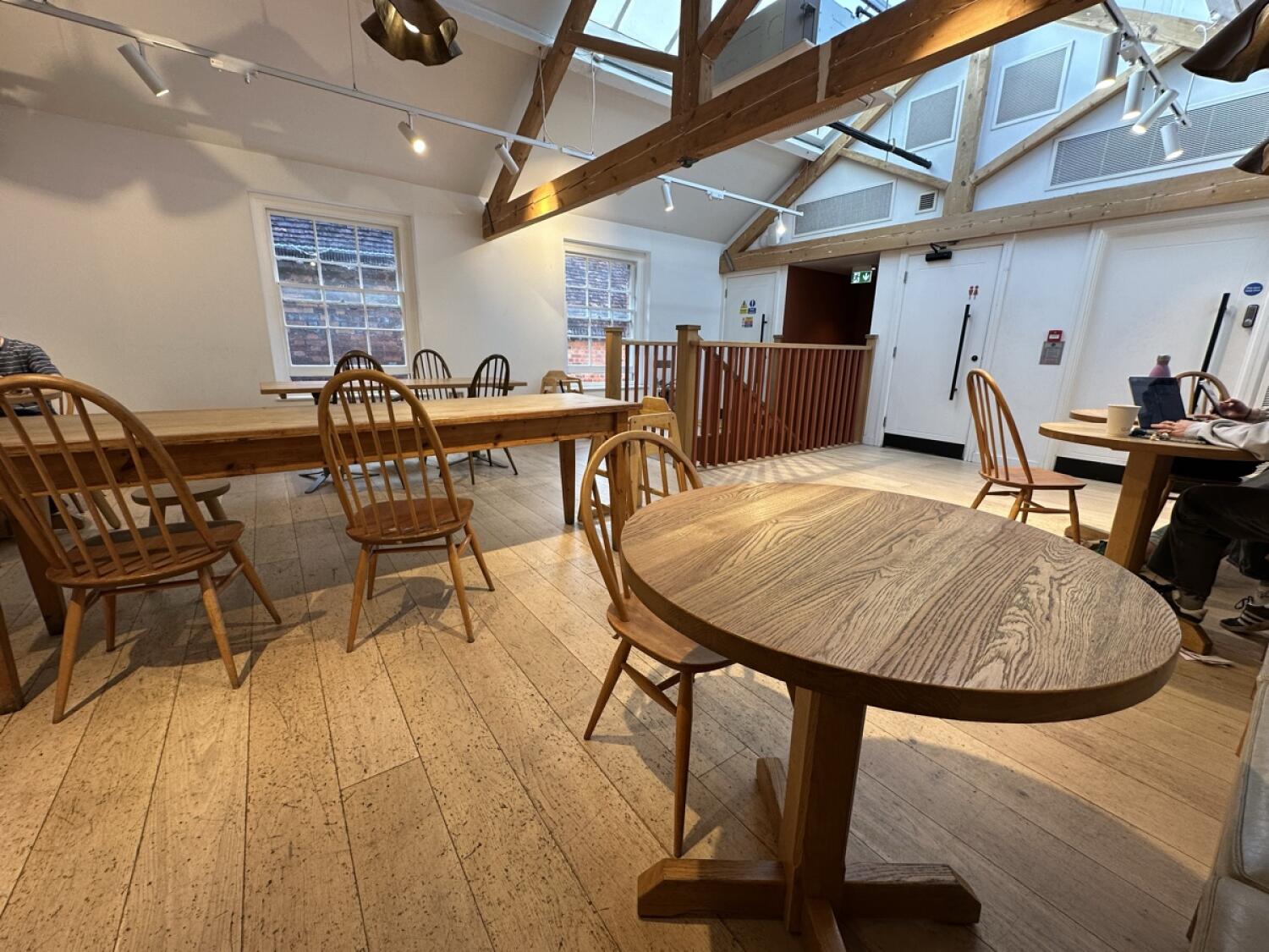 Tables and chairs along left. Railing around central stair opening. Tables and chairs along right.