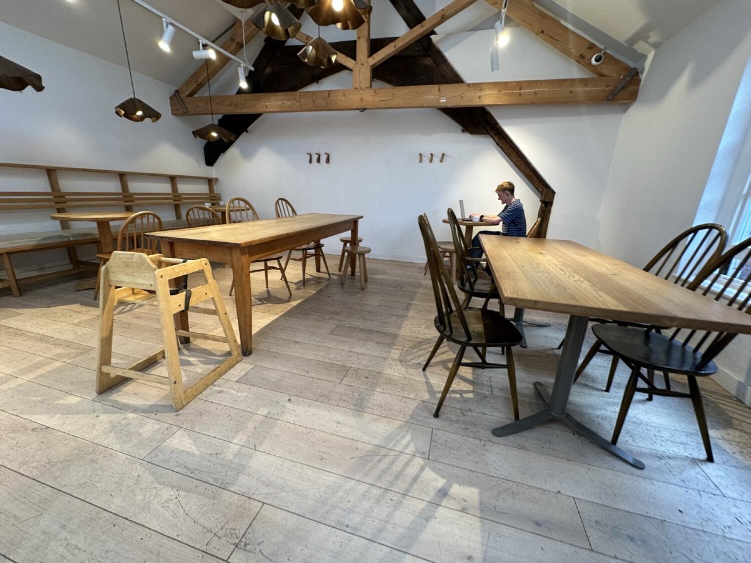 Baby high chair and benches left. Large table and chairs centre. Tables and chairs along right.