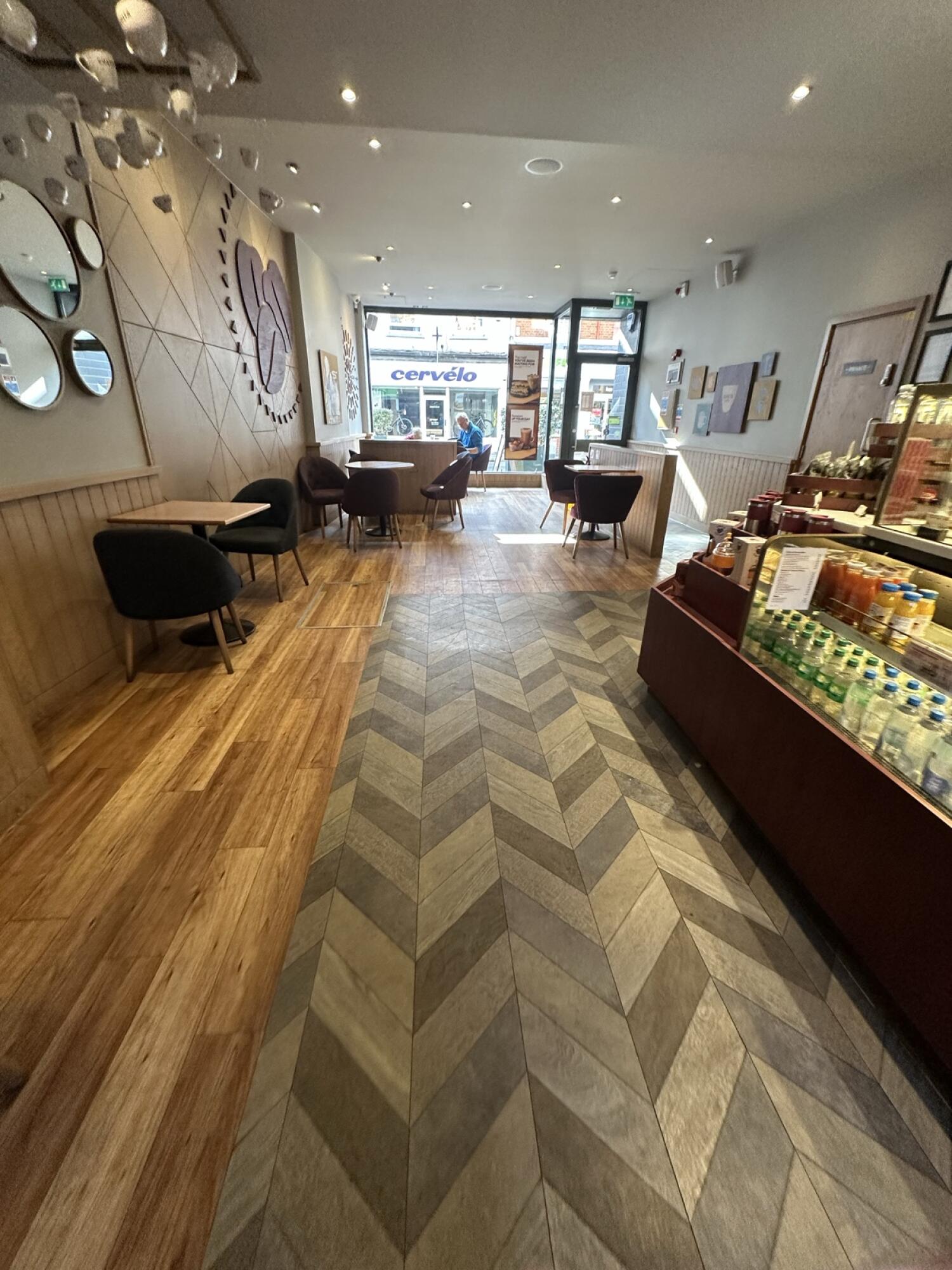 Tables and chairs along left. Tiled path through centre. Display counter along right.