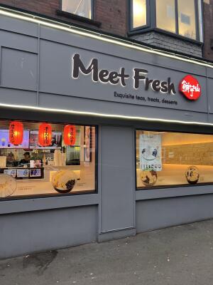 Service counter window on left. Grey door in centre. Display window on right.
