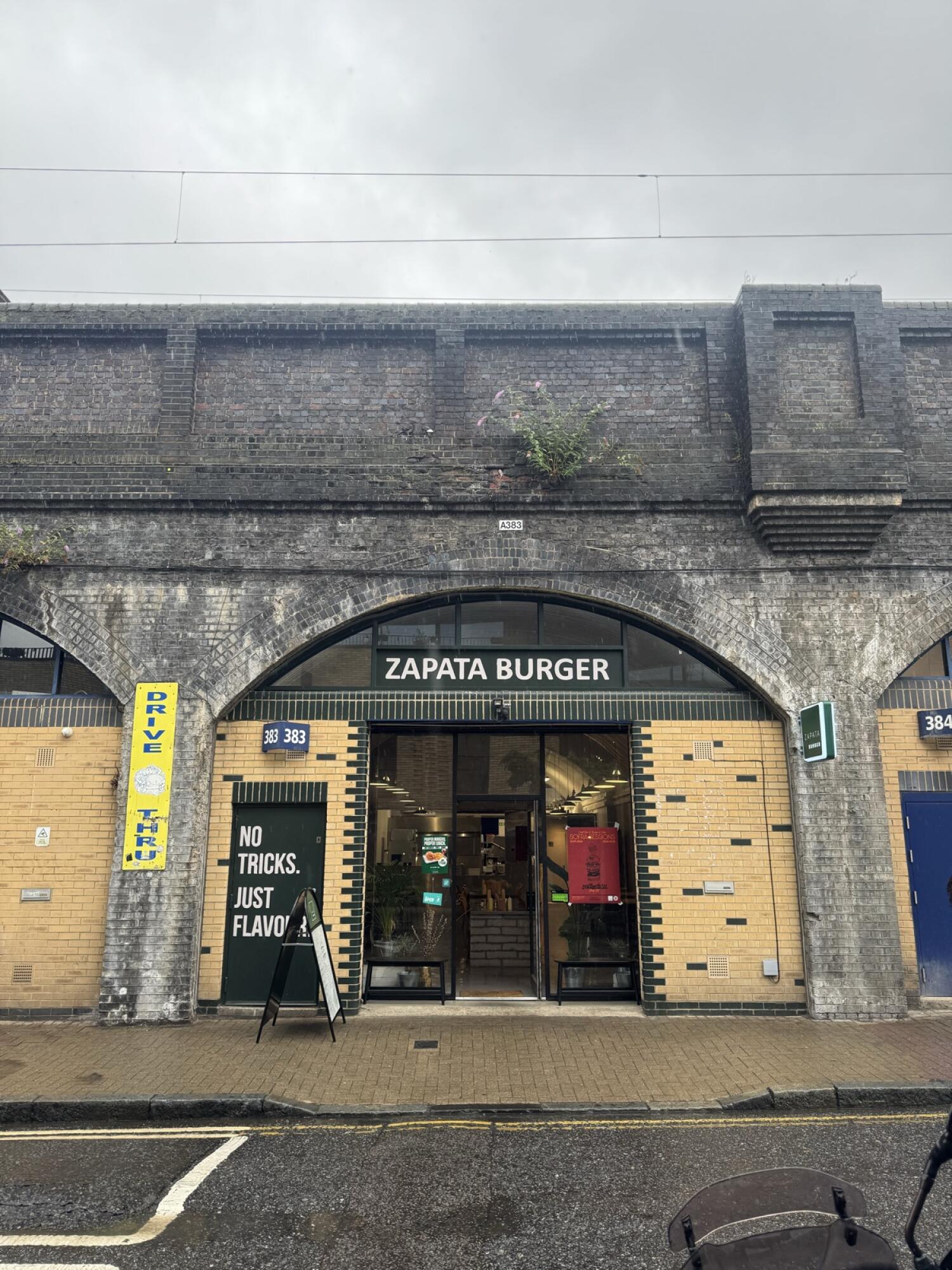 Black metal-framed glass doors. Entrance under brick arch.
