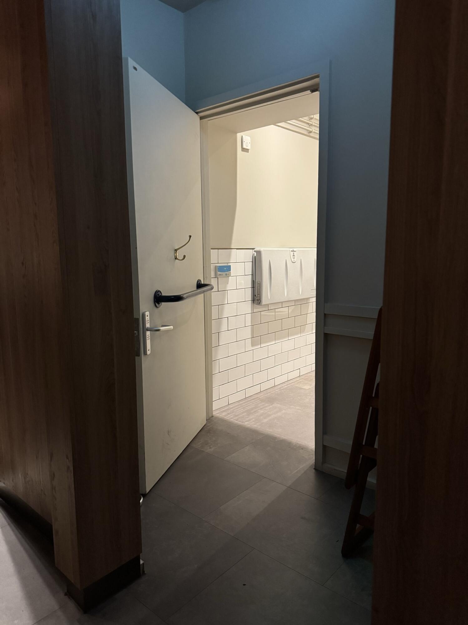White wooden door. Use handle to open.