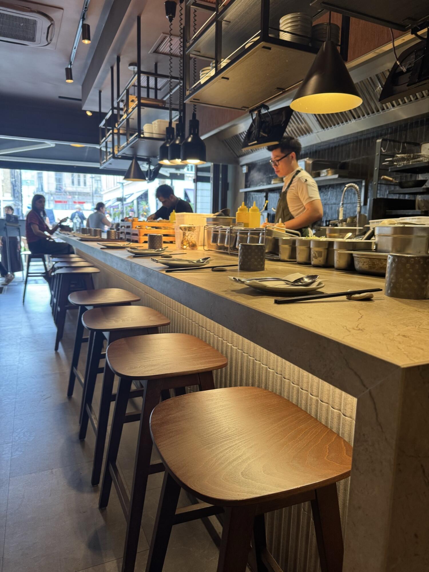 Path along left. Counter seating in centre. Open kitchen along right.