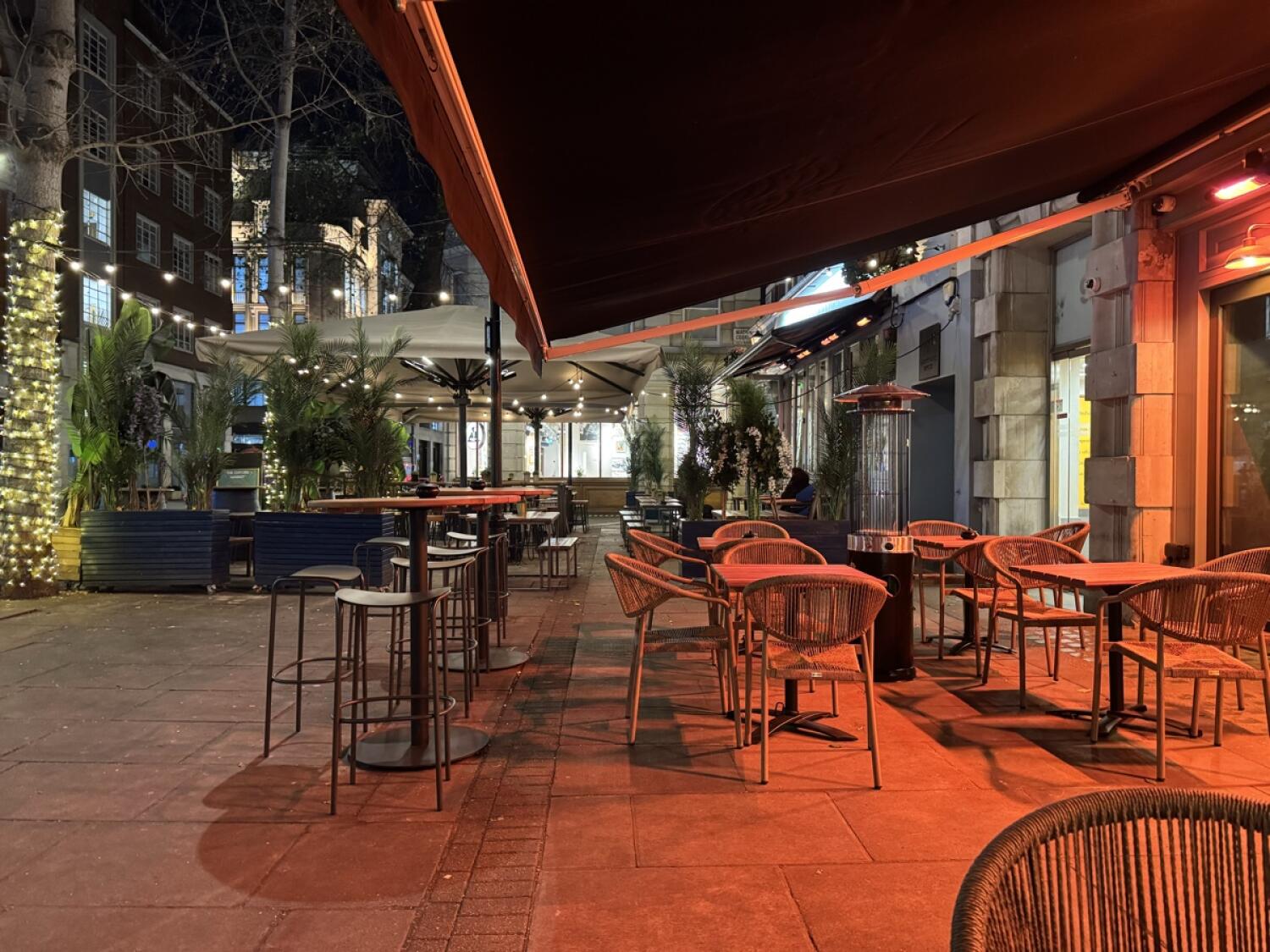High tables and stools left. Path through centre. Tables and chairs along right.