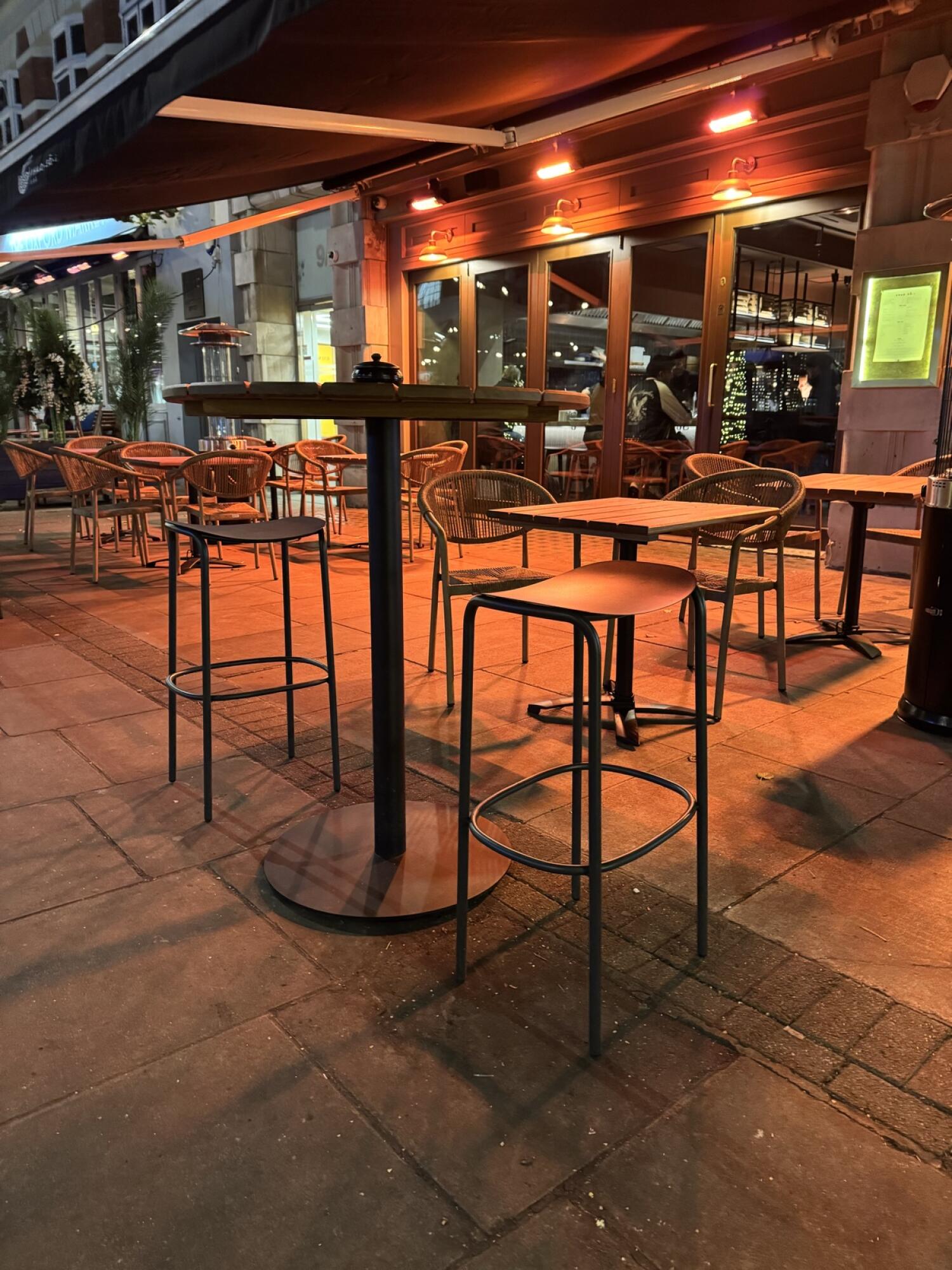 Tables and chairs along left. High tables and stools in centre. Entrance doors and seating right.