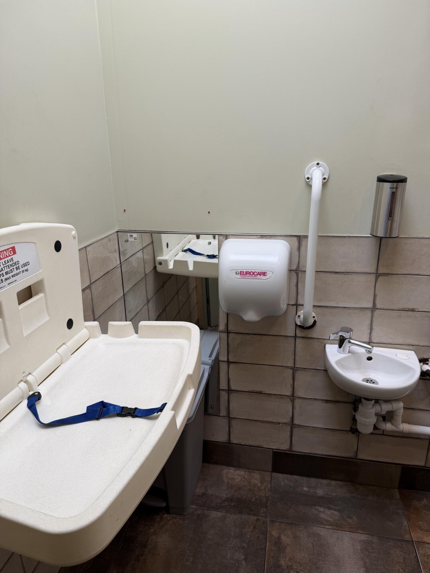 Baby changing station on left. Sink on right wall.