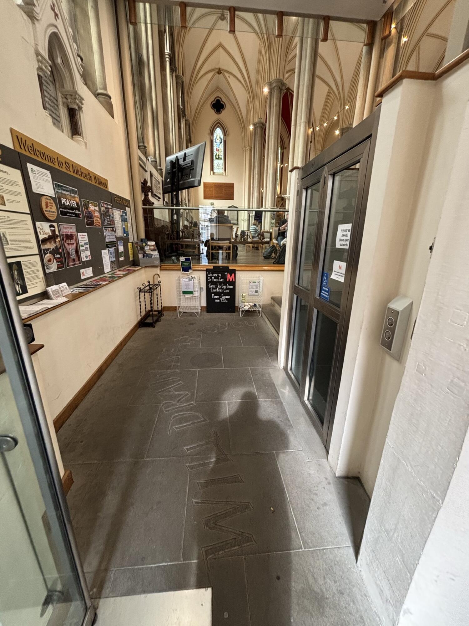 Noticeboard along left wall. Tiled path through centre. Steps and platform lift on right.