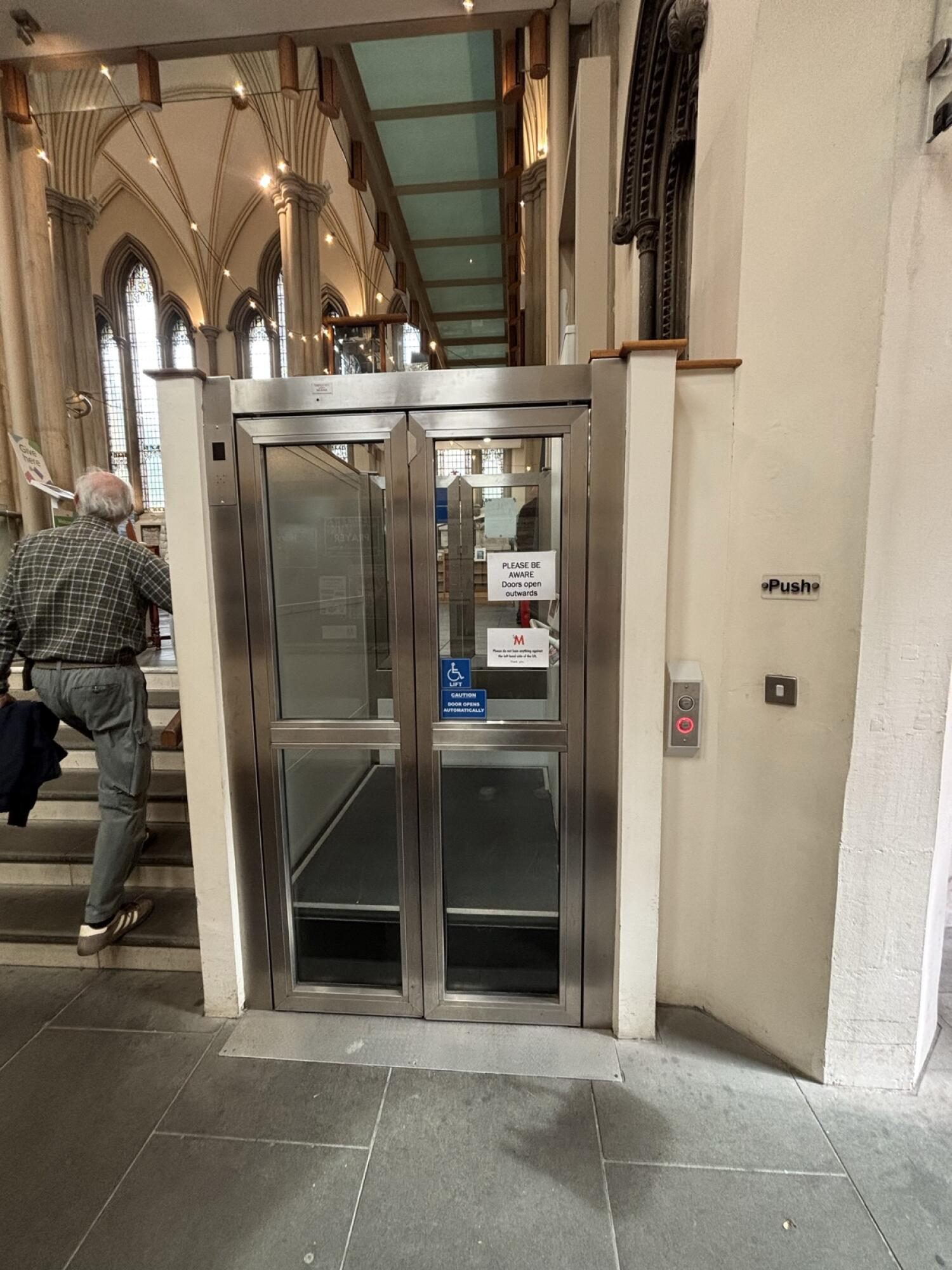 Metal-framed glass lift doors. Push button to open.