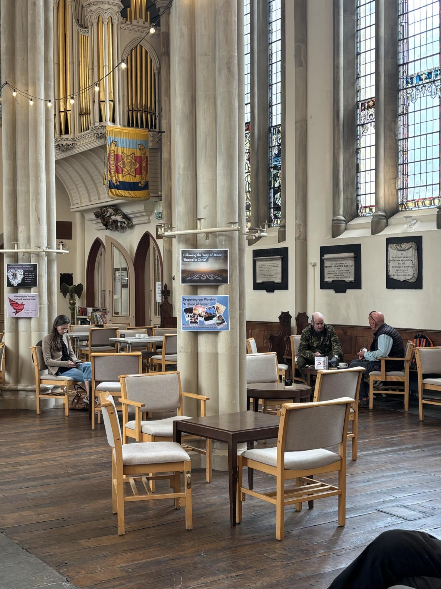 Chairs and tables throughout space. Pillars in centre. Seating along right wall.