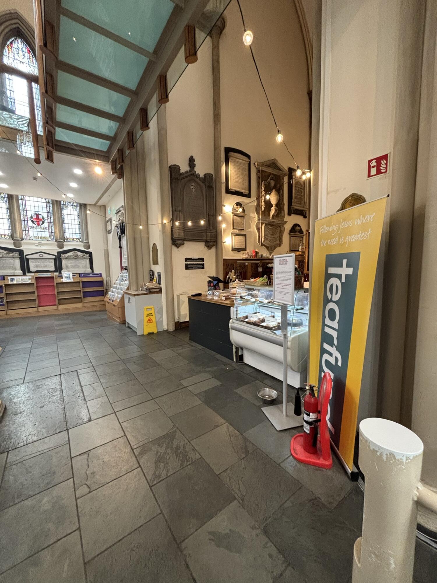 Product shelves along left. Open tiled floor in centre. Display counter along right.
