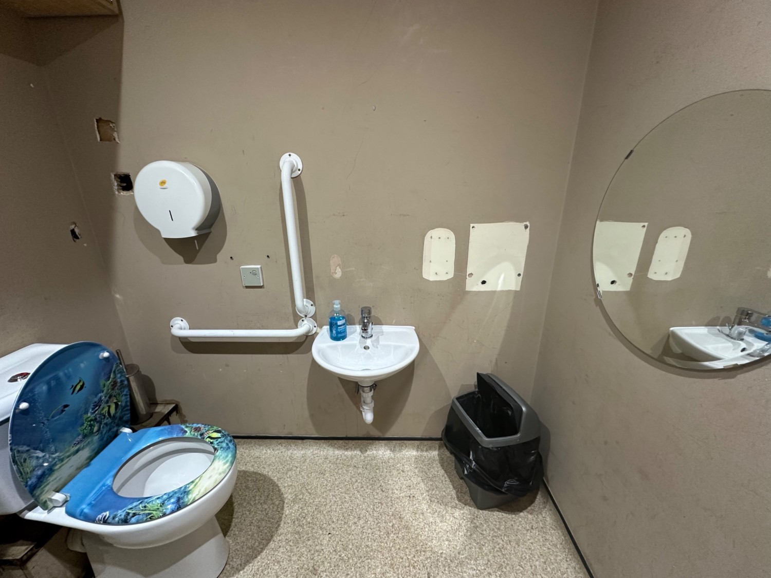 From bathroom door looking straight at toilet to far left. Sink on back wall ahead.