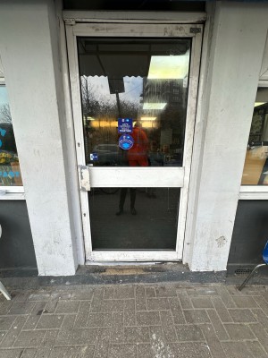 Glass door with white frame. Push towards left to open.