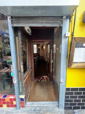 Glass door. Push open via silver vertical handle on left.