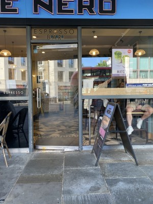 Glass door with grey frame ahead. Pull from metal handle on left to open