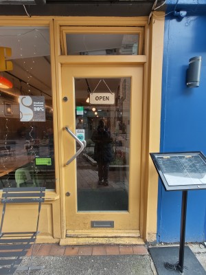 Yellow framed glass door. Push silver handle on left to open.