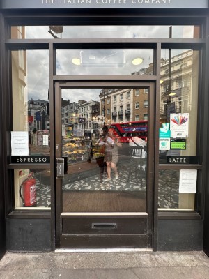 Glass door with brown doorframe. Brown handle to left, push to open.