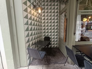 From left of venue, facing right. Table and chairs ahead. Door on back right. Path in middle.