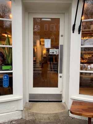Glass door with white wooden frame. Push from right to open.