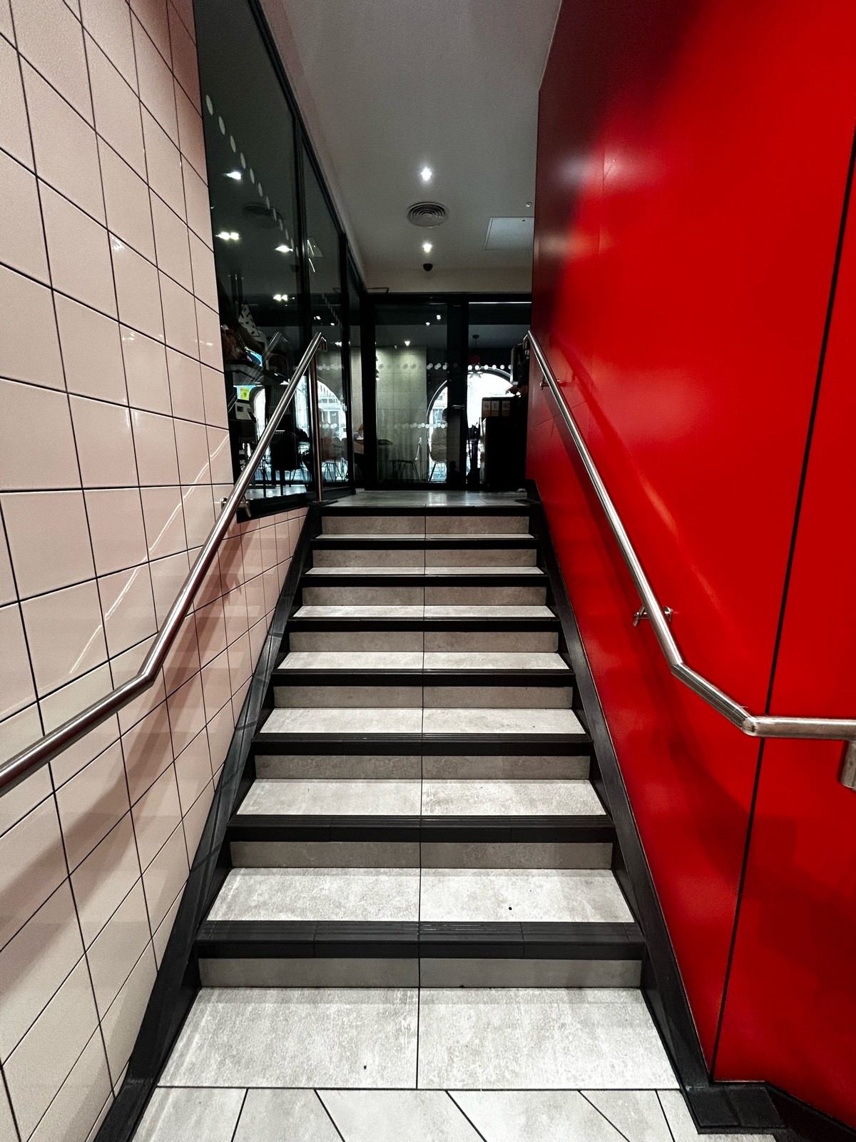 From second landing area, facing straight. Stairs ahead with silver handrails on both sides.