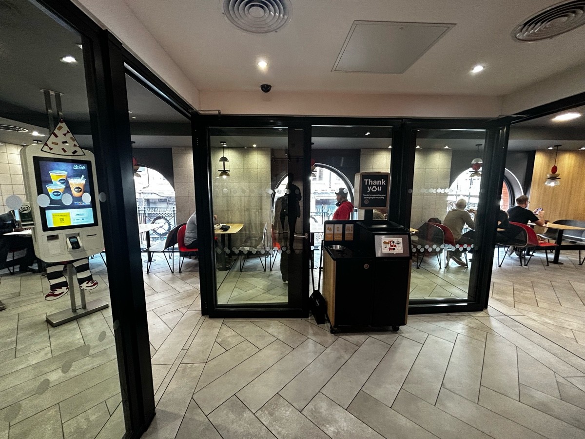 From end of stairs, facing straight. Path ahead leading to seating area on both left and right of back glass wall. Beware of shelve on back wall ahead