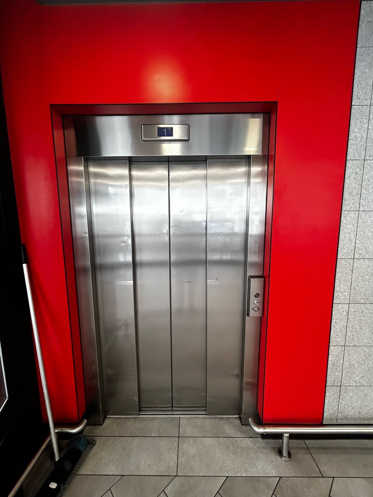 From main area, facing left. Lift ahead. Buttons on mid right. Push to call the lift.