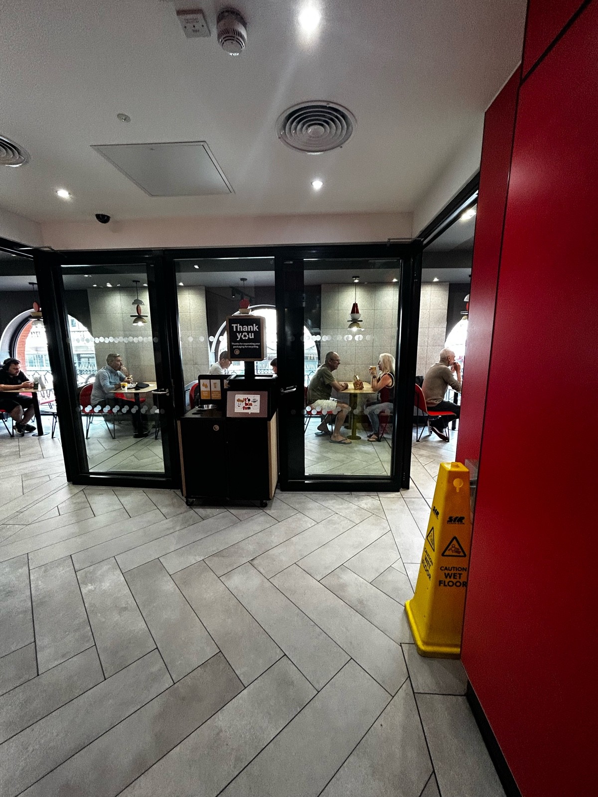 From lift door, facing straight. Upstairs level path ahead leading to preceding doors and seating on both left and right.
