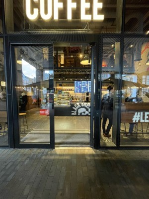 Black-framed glass door. No handles. Push from centre to open.