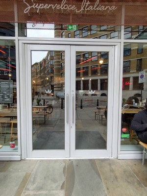 Glass doors with white frame. Pull silver vertical handles in the middle to open.