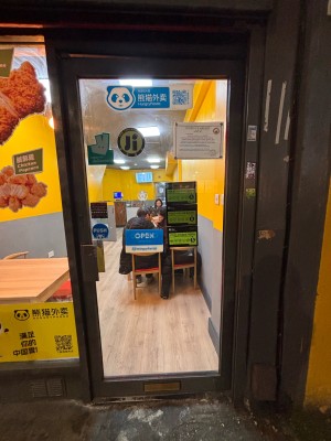 Glass door with grey metal frame ahead. Push grey metal handle at left to open.