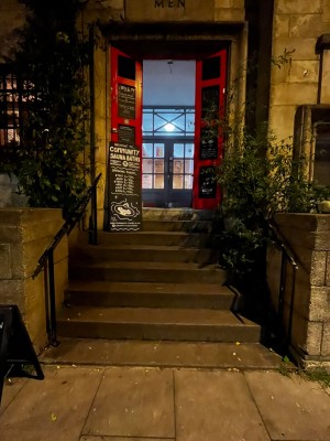 Black and red double doors, pull from middle to open. 6 steps up to door, one further step through door. Handrails both sides. Small bump before steps