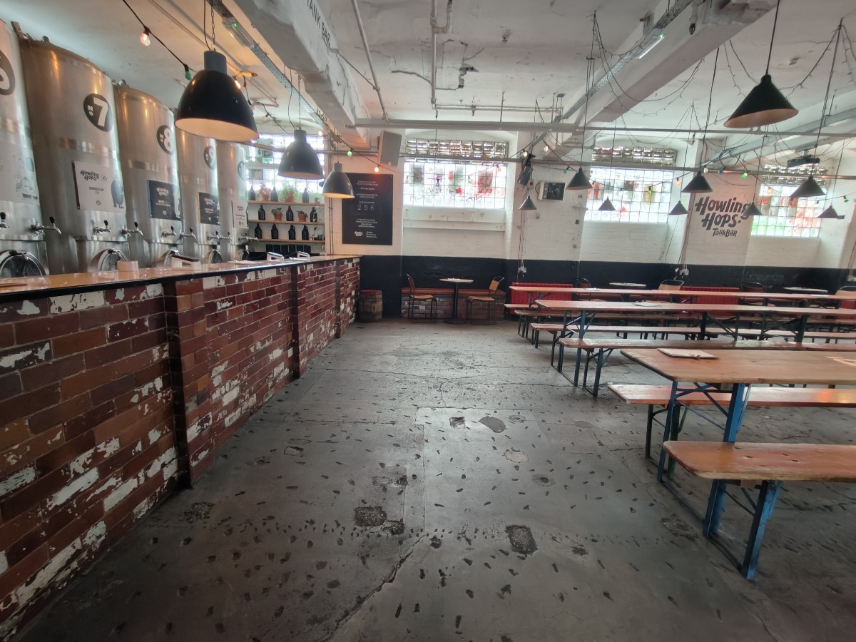 From after storage facing straight. Bar along left. Tables and chairs at back. Tables and benches on right.