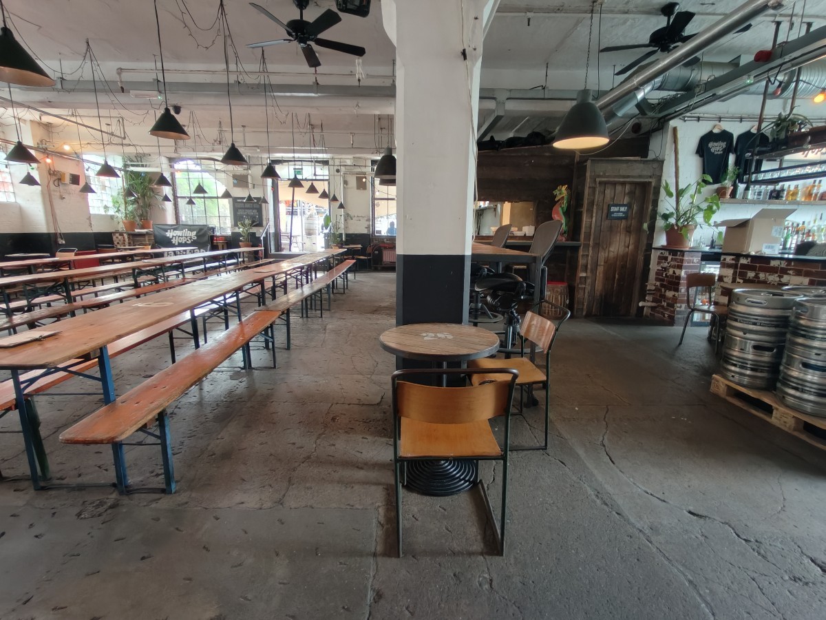 From after storage facing right. Table and chairs at back. High table behind. Tables and benches along left.