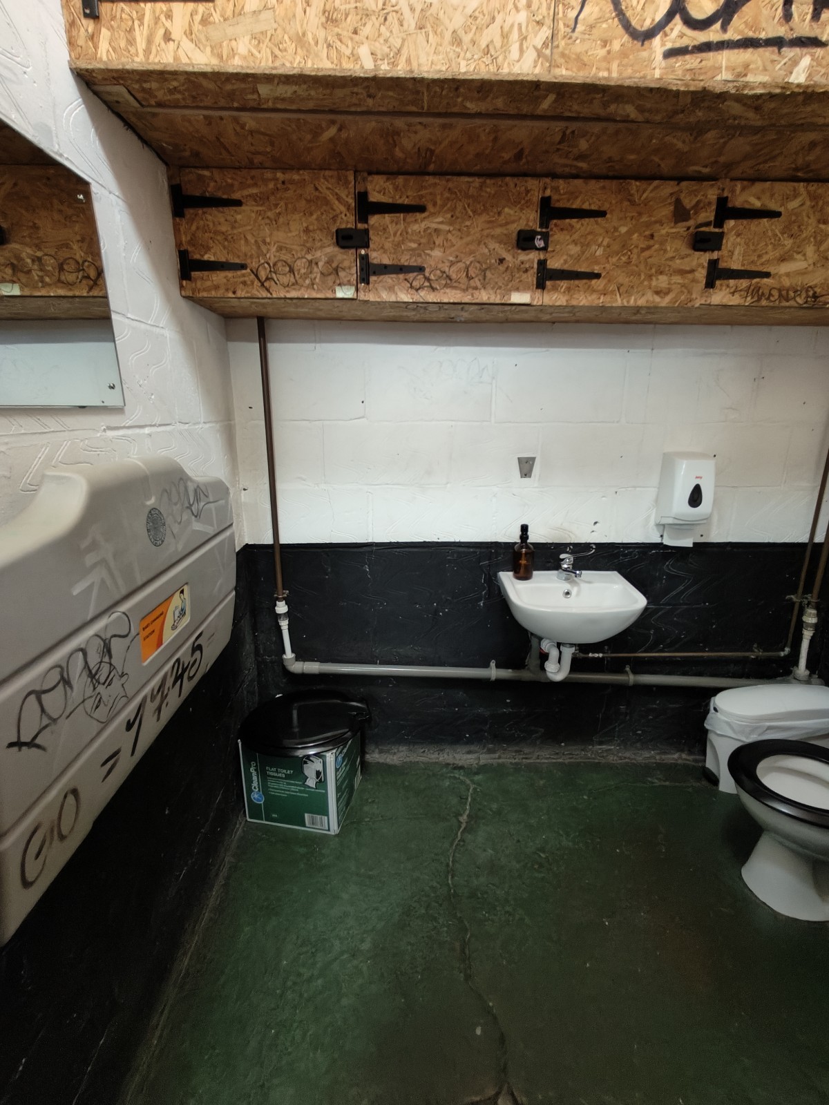 From door facing straight. Baby change table on left wall. Sink at back right. Toilet on right.