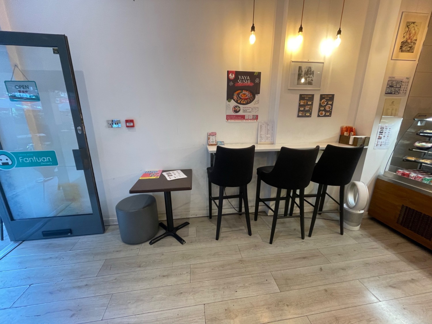 From the entrance, looking left. Standing height tables and stools along the back wall, counter at right.